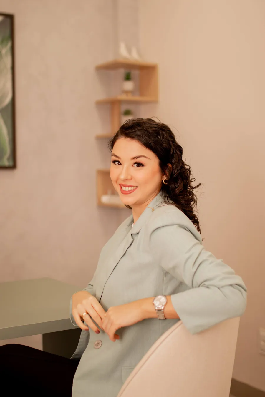 Priscila Figueiredo sorrindo, sentada, em ambiente aconchegante em tons terrosos
